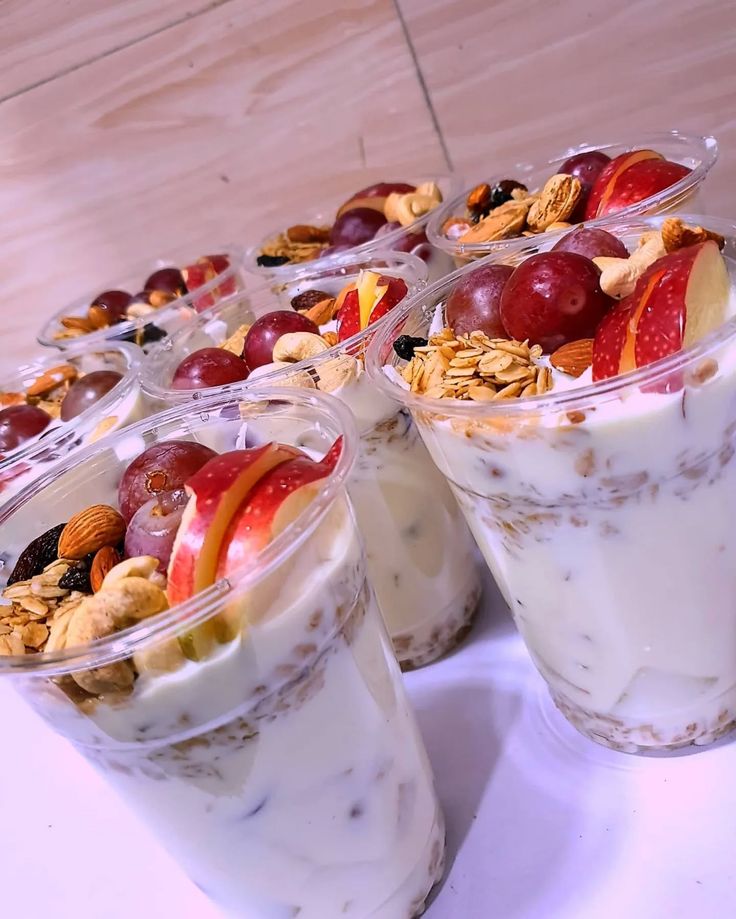 Fruit parfait cups layered with yoghurt, granola, grapes, apple and nuts