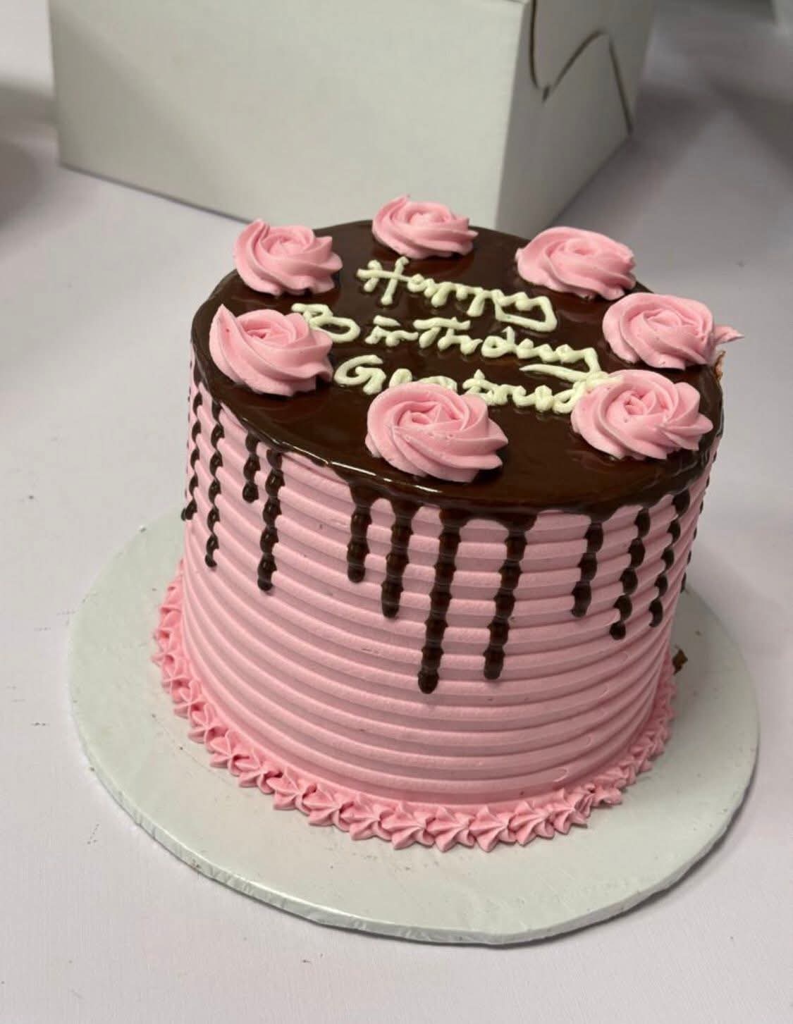 Pink buttercream celebration cake with chocolate drip and piped roses